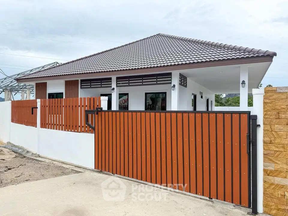 Charming single-story home with modern fence and tiled roof, perfect for family living.