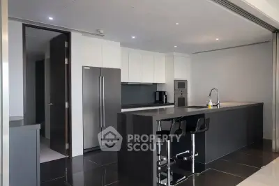 Modern kitchen with sleek design, featuring a large island, stainless steel appliances, and stylish bar stools.