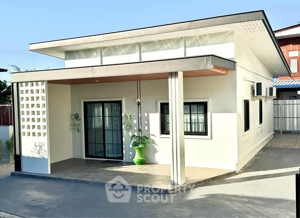 Modern single-story house with minimalist design and large windows, featuring a spacious front porch.