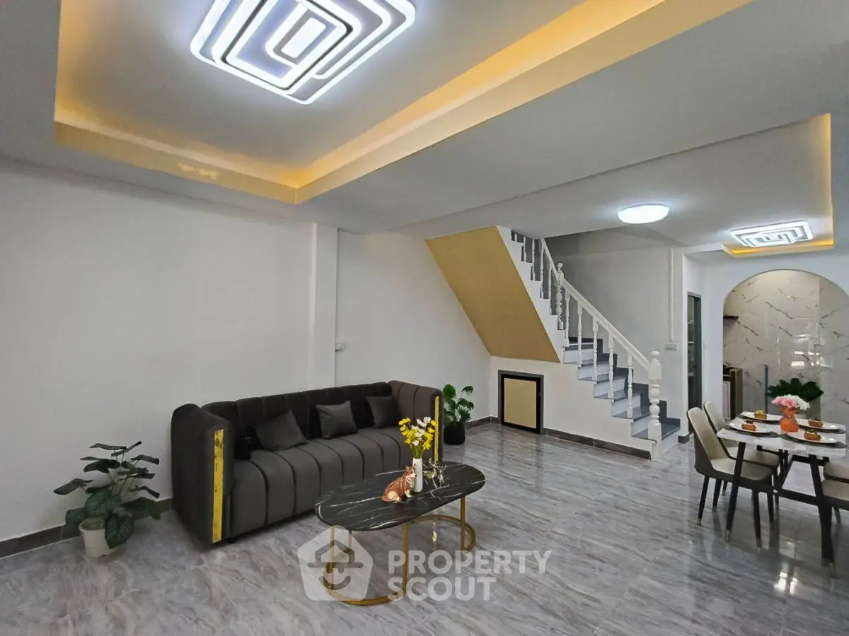 Modern living room with stylish sofa, elegant staircase, and chic dining area