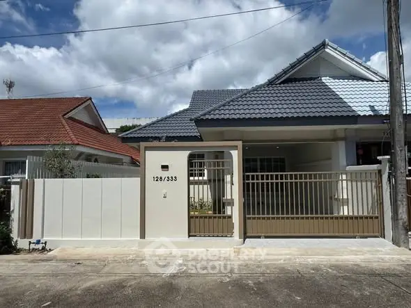 Charming single-story house with modern roof and gated entrance in a serene neighborhood.