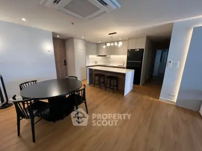 Modern open-layout kitchen and dining area with sleek design and wooden flooring.