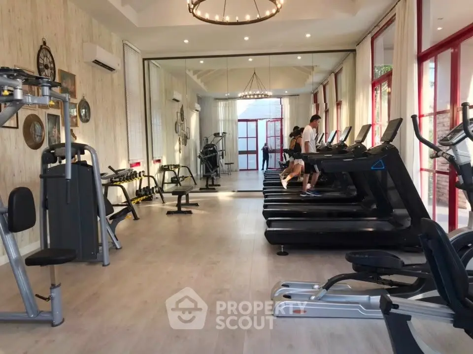 Spacious gym with modern equipment and elegant lighting in a luxury residential building.