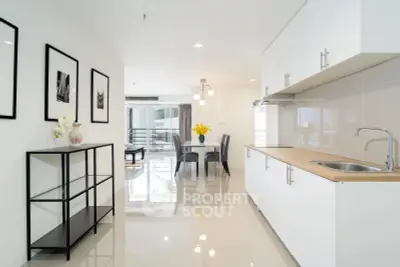 Modern open-plan kitchen and dining area with sleek white cabinets and stylish decor.