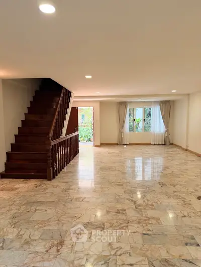 Spacious living room with elegant staircase and marble flooring, perfect for modern family living.
