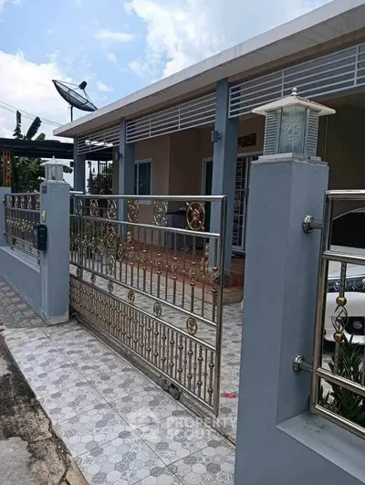 Charming single-story home with decorative metal gate and tiled driveway, perfect for modern living.