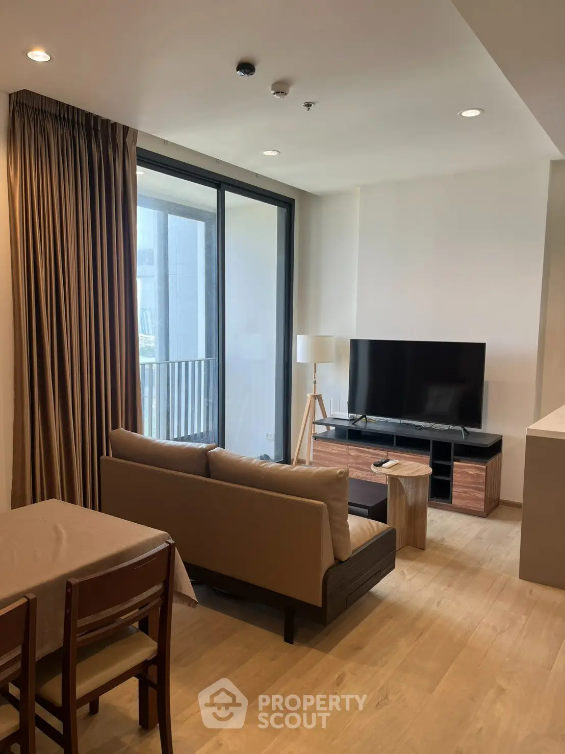 Modern living room with large TV, cozy sofa, and balcony access in a stylish apartment.