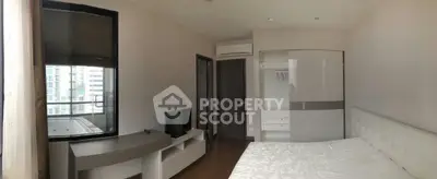 Modern bedroom with large window and built-in wardrobe in a high-rise apartment.