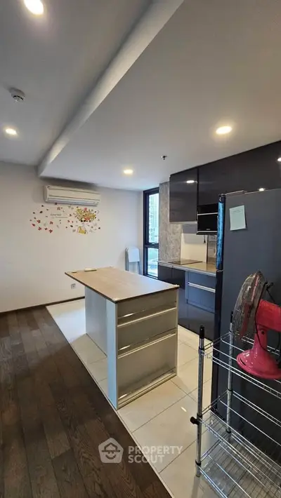 Modern kitchen with island, sleek cabinets, and wooden flooring in a stylish apartment.