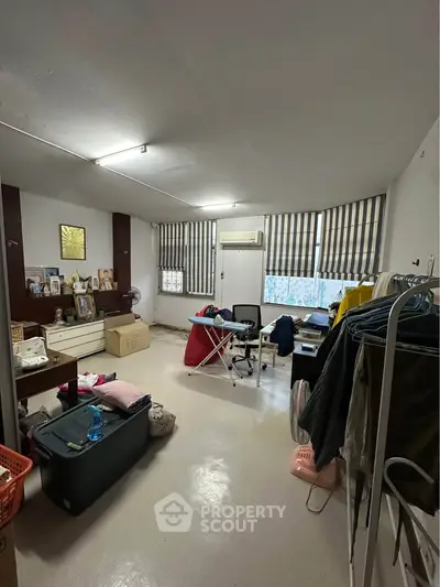 Spacious room with ample natural light, featuring a desk, chair, and storage solutions, ideal for versatile use.