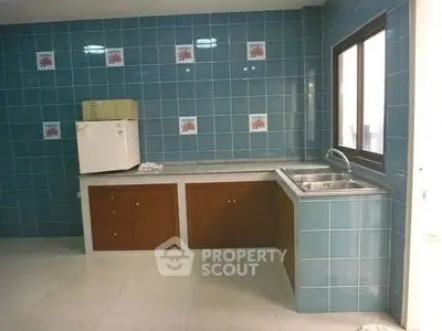Spacious kitchen with blue tiled walls and modern sink