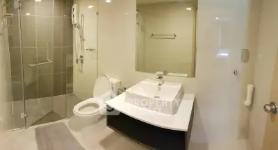 Modern bathroom with sleek fixtures and glass shower enclosure in a contemporary apartment.