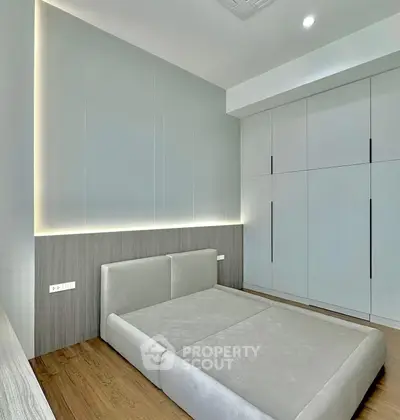 Modern minimalist bedroom with sleek built-in wardrobe and elegant lighting.