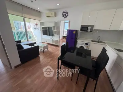 Modern open-plan living room with kitchen, featuring sleek furniture and city view balcony.