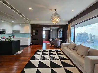 Luxurious open-plan living room with city view, elegant chandelier, and modern kitchen.