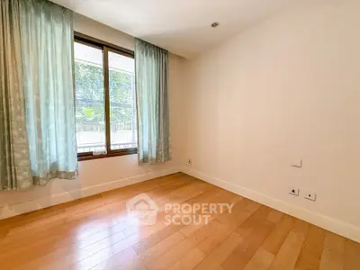 Spacious empty room with wooden flooring and large window view