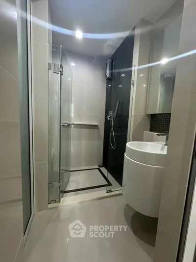 Modern bathroom with glass shower and sleek fixtures in contemporary apartment.