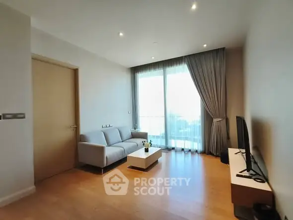 Modern living room with sleek furniture and large window offering natural light.