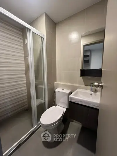 Modern bathroom with glass shower and sleek fixtures in a contemporary apartment.