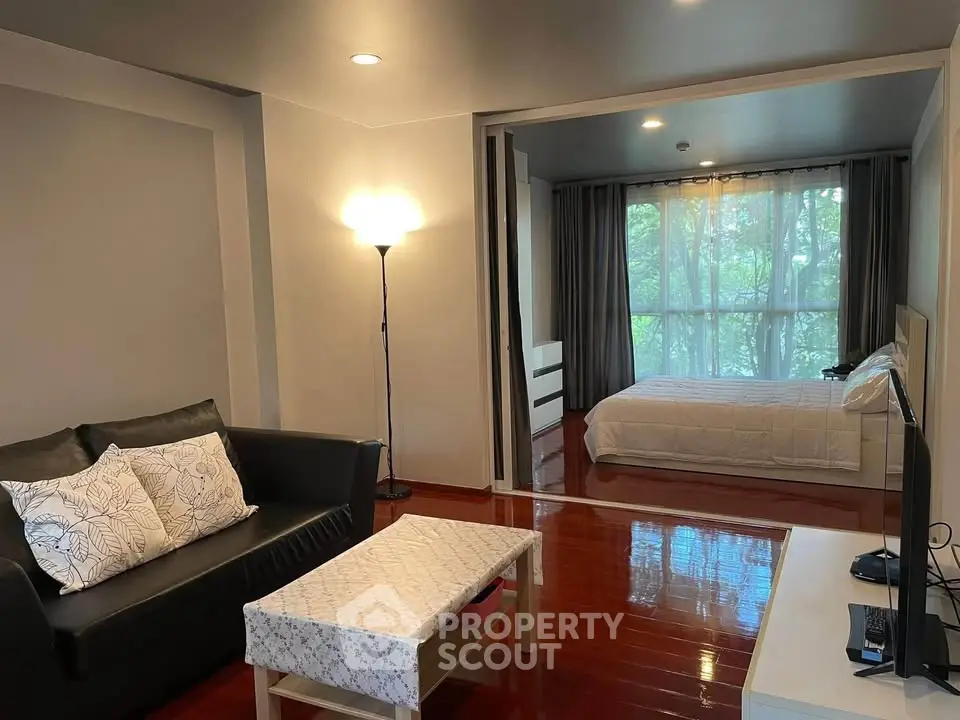 Spacious open-plan living room with cozy bedroom and large window view.