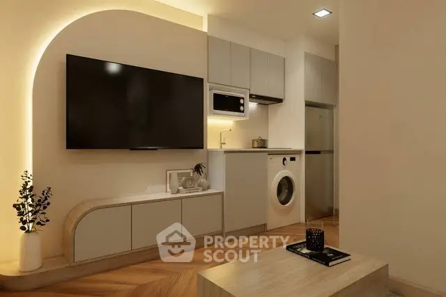 Modern living room with sleek TV setup and compact kitchen appliances.