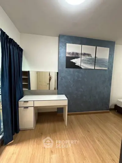 Modern bedroom with stylish decor and wooden flooring, featuring a sleek desk and ocean-themed artwork.