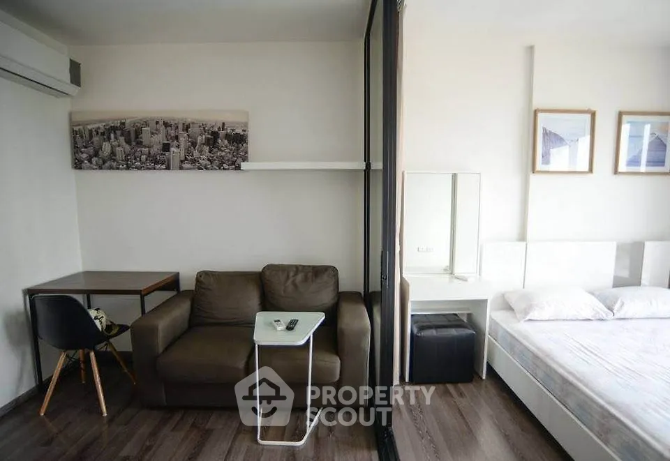 Modern studio apartment with cozy living area and stylish bedroom separated by glass partition.
