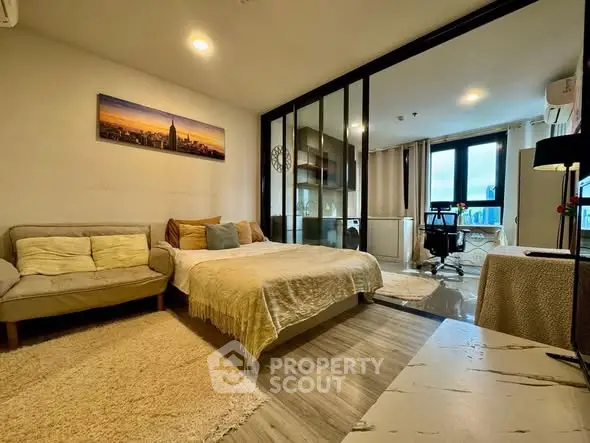 Modern studio apartment with cozy living area and workspace, featuring large windows and stylish decor.