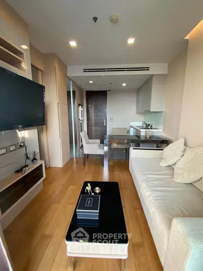 Modern living room with open kitchen, wooden flooring, and stylish furniture in a cozy apartment.