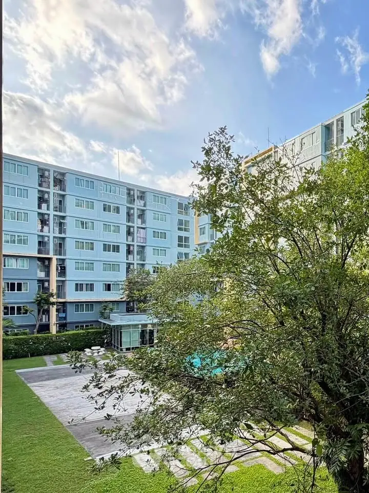 Modern apartment building with lush garden and clear blue sky view.