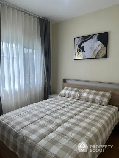 Cozy bedroom with checkered bedding and modern art on the wall, perfect for relaxation.