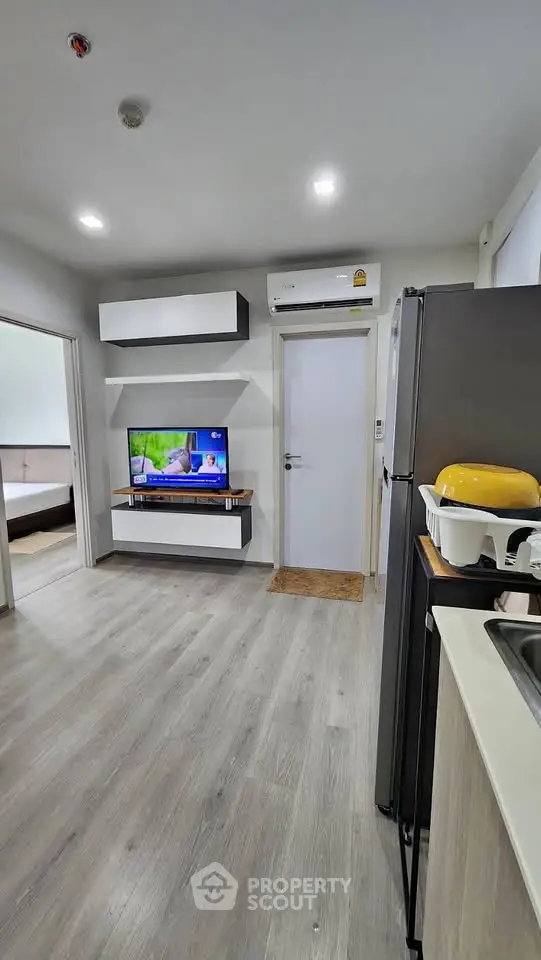 Modern apartment interior with sleek kitchen and cozy living area featuring TV and air conditioning.