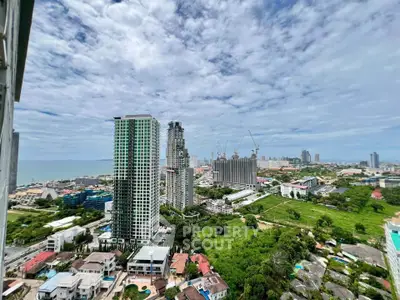 Stunning cityscape view from high-rise building with lush greenery and ocean backdrop.
