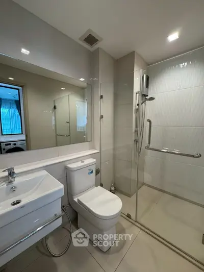 Modern bathroom with sleek fixtures and glass shower enclosure in a contemporary apartment.
