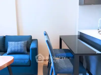 Modern living room with blue sofa and dining area in stylish apartment.