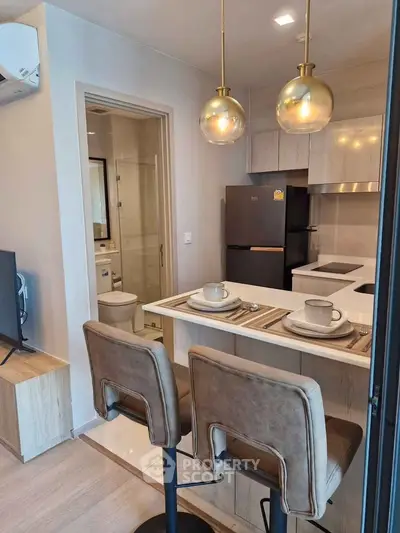 Modern kitchen with stylish bar seating and sleek appliances in a cozy apartment.