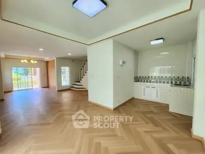 Spacious open-plan living area with modern kitchen and elegant wooden flooring.