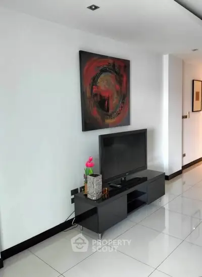 Modern living room with sleek TV stand and abstract art on white walls.