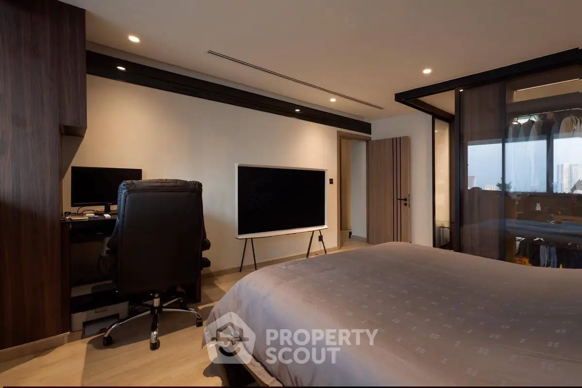 Modern bedroom with sleek design, featuring a large TV and workspace, ideal for urban living.