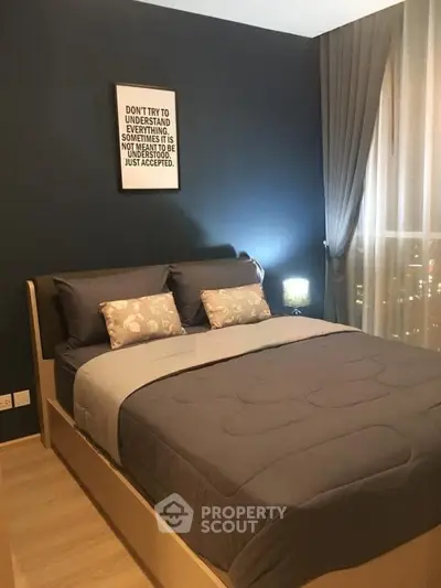 Cozy bedroom with modern decor and large window offering natural light.