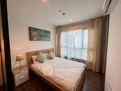 Cozy bedroom with modern decor and large window for natural light.