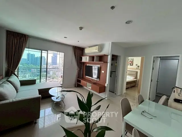 Modern living room with city view, stylish furniture, and open layout in high-rise apartment.