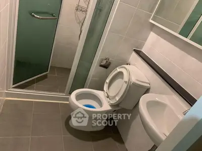Compact bathroom with shower, toilet, and sink in modern apartment.