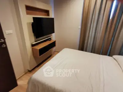 Cozy bedroom with modern TV setup and elegant curtains, perfect for relaxation.