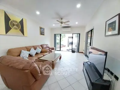 Spacious living room with leather sofas, modern decor, and large TV, perfect for relaxation and entertainment.