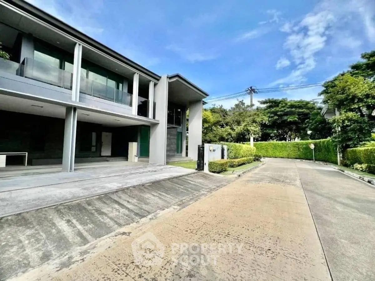 Modern two-story house with spacious driveway and lush greenery in a serene neighborhood.
