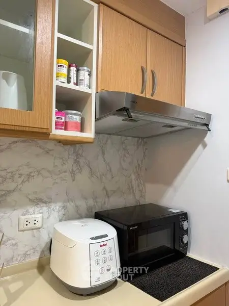 Modern kitchen with microwave and rice cooker on marble countertop