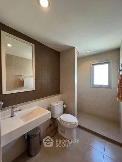 Modern bathroom with sleek fixtures and natural light, featuring a spacious shower area.