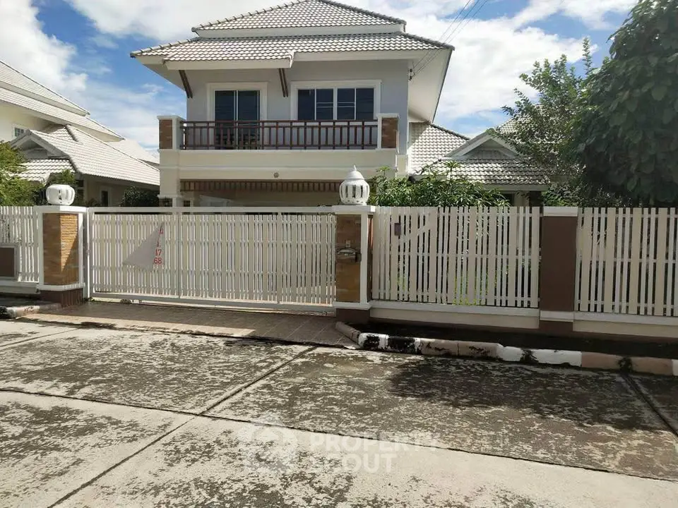 Charming two-story house with gated entrance and lush greenery, perfect for family living.