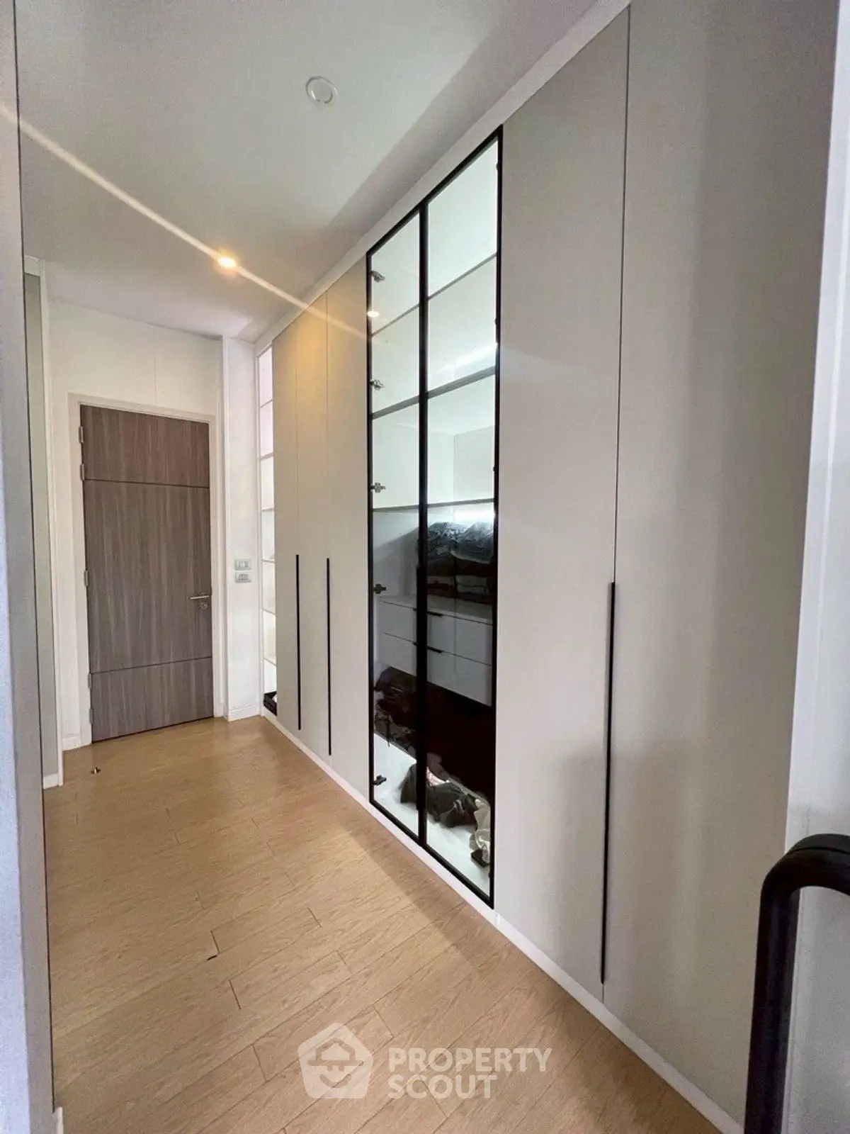 Sleek modern hallway with built-in mirrored wardrobe and wooden flooring.